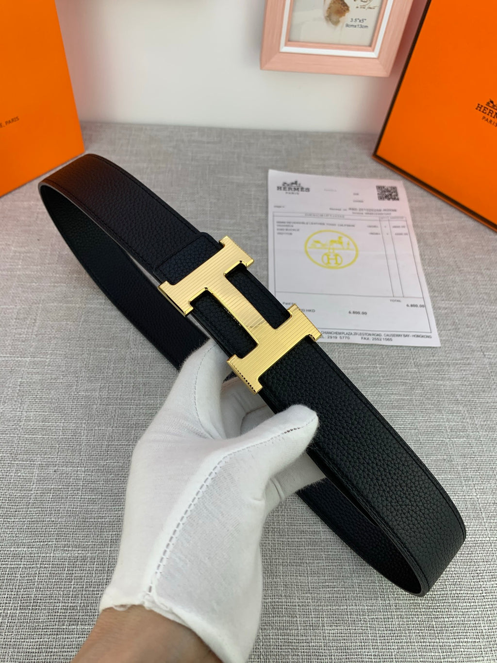 Black leather belt with textured finish and gold-tone H buckle