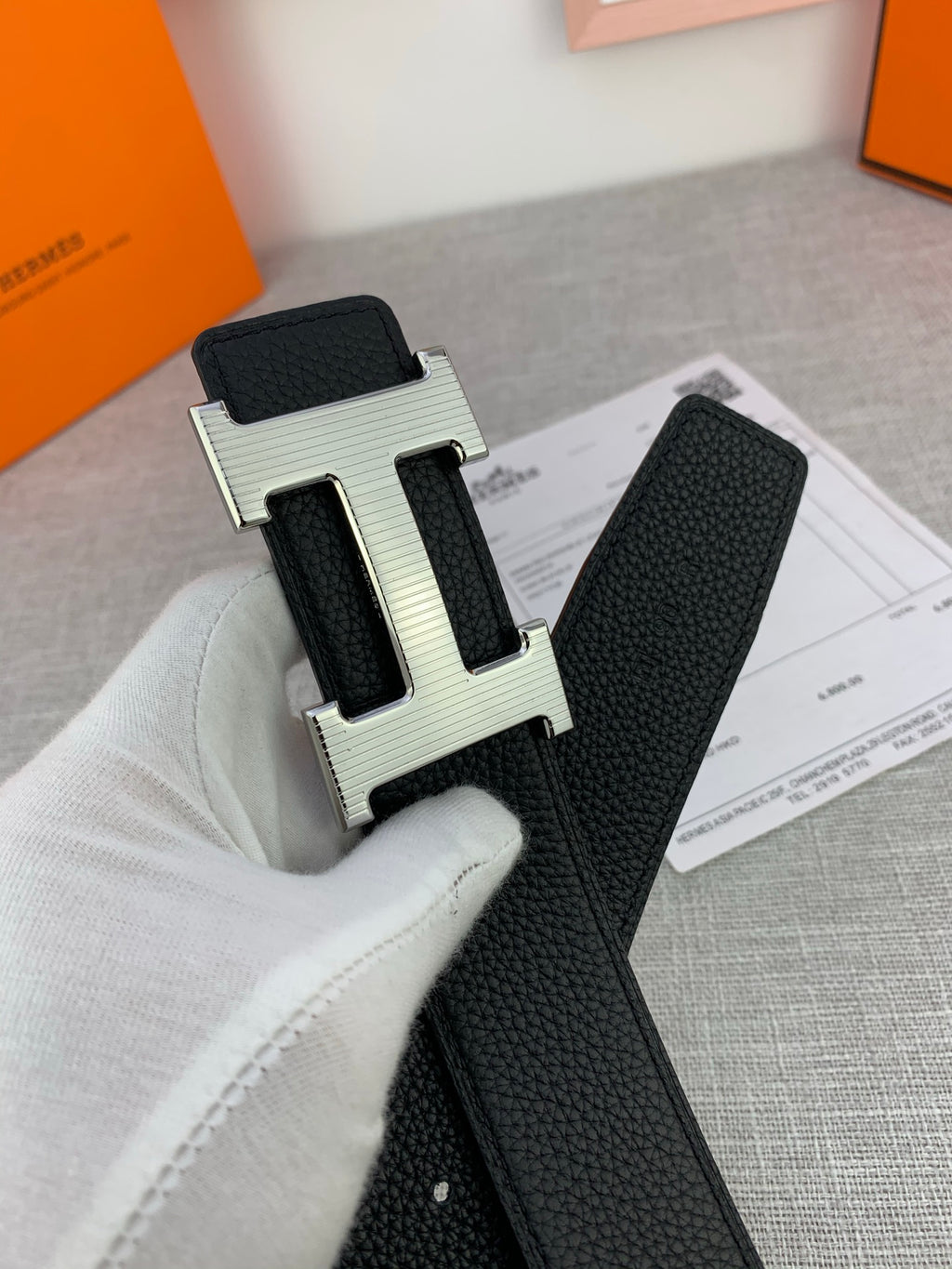 Close-up of black leather belt with textured strap and silver-tone H buckle