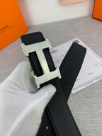 Close-up of black leather belt with textured strap and silver-tone H buckle