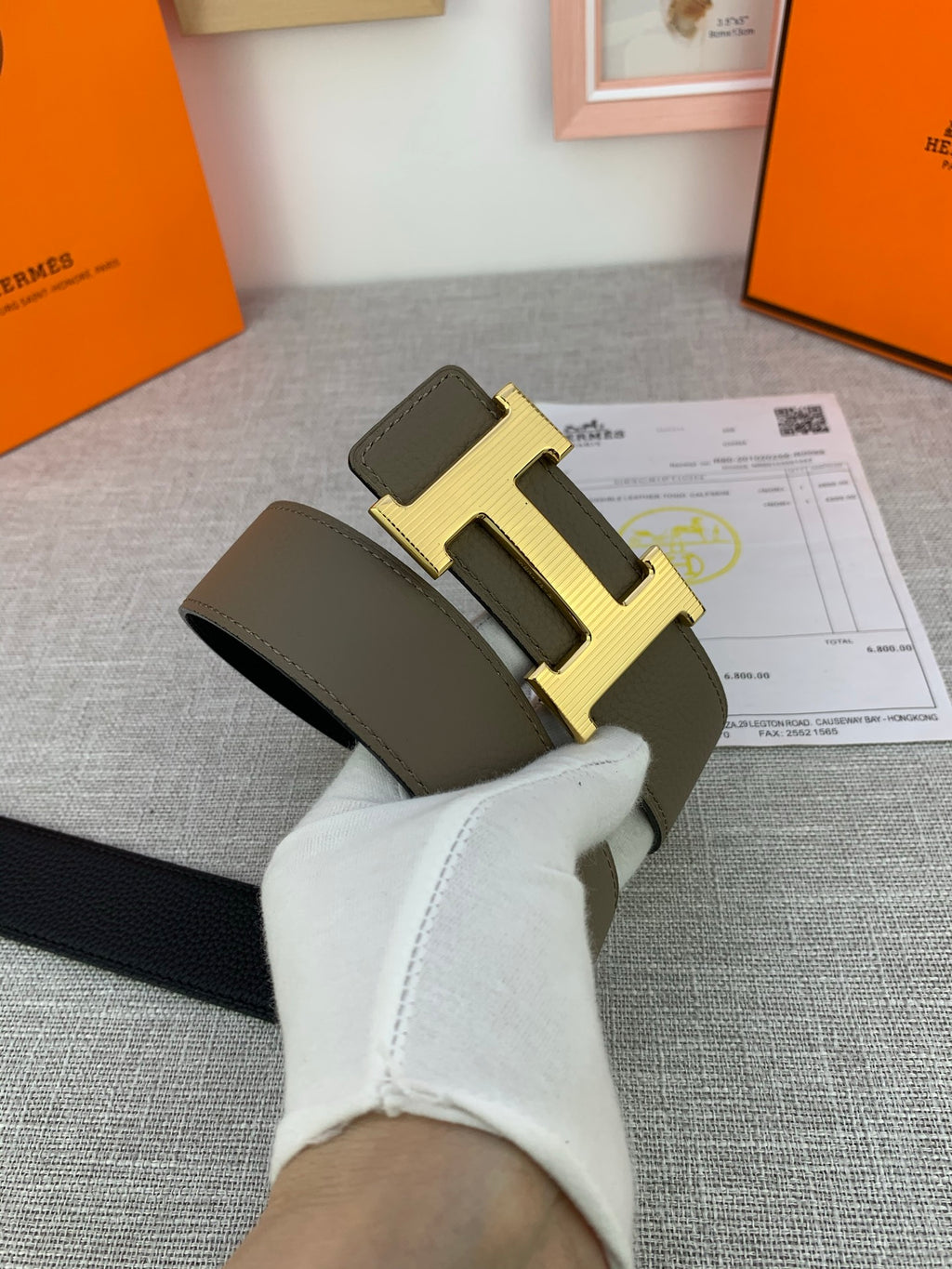 Reversible leather belt on cloth: light olive strap with gold-tone H buckle and black side.