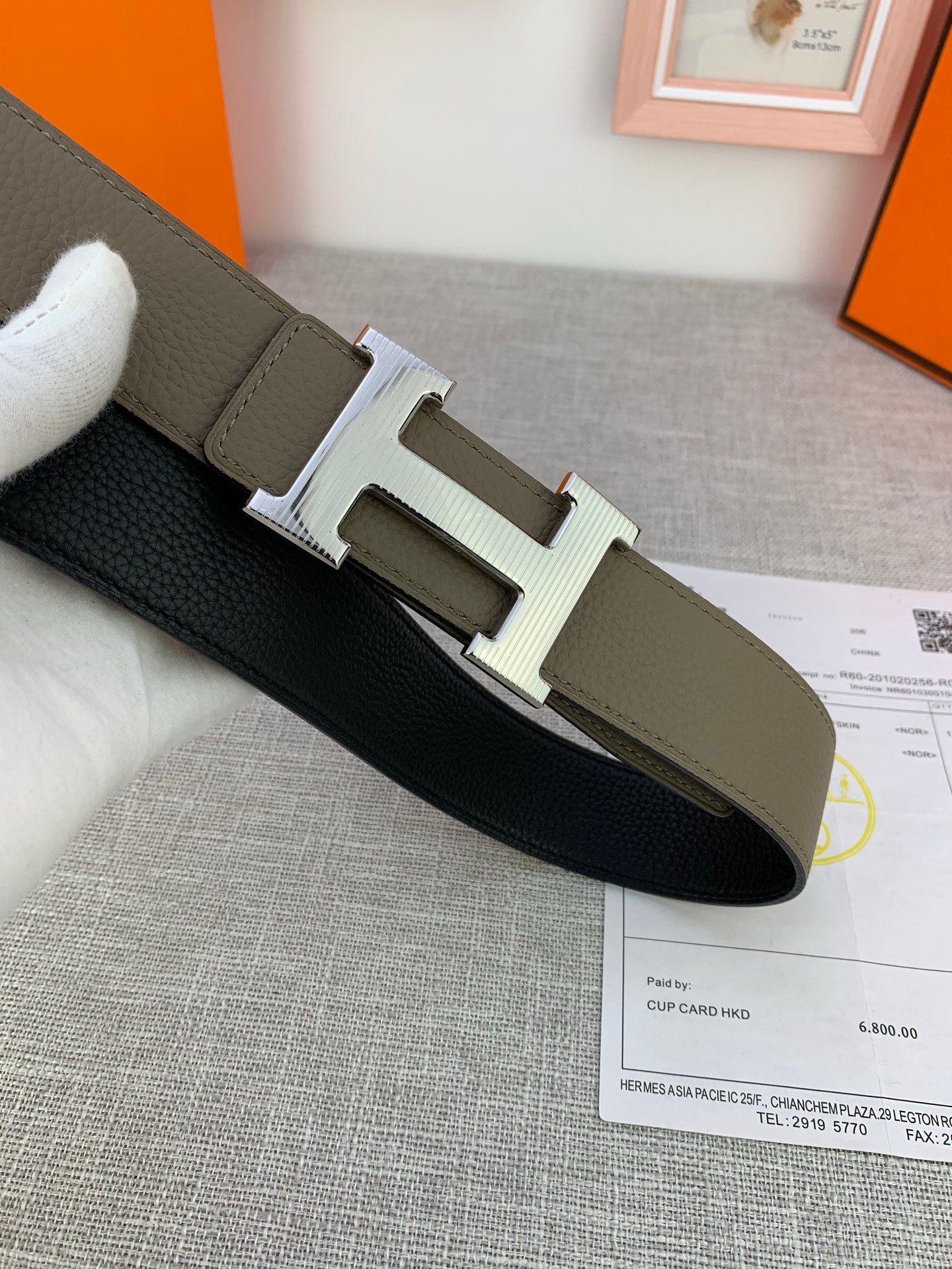 Reversible leather belt with H buckle; light olive face and black underside on display.