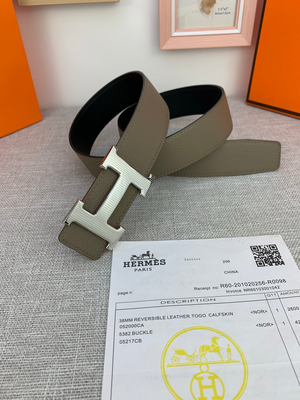 Reversible leather belt with light olive and black sides; large gold-tone H buckle.