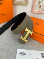 Reversible leather belt with dark leather underside and light olive face; gold-tone H buckle.