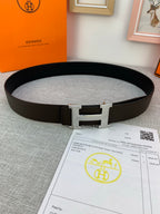 Hermes belt dark leather with silver-toned buckle clasp on light gray surface