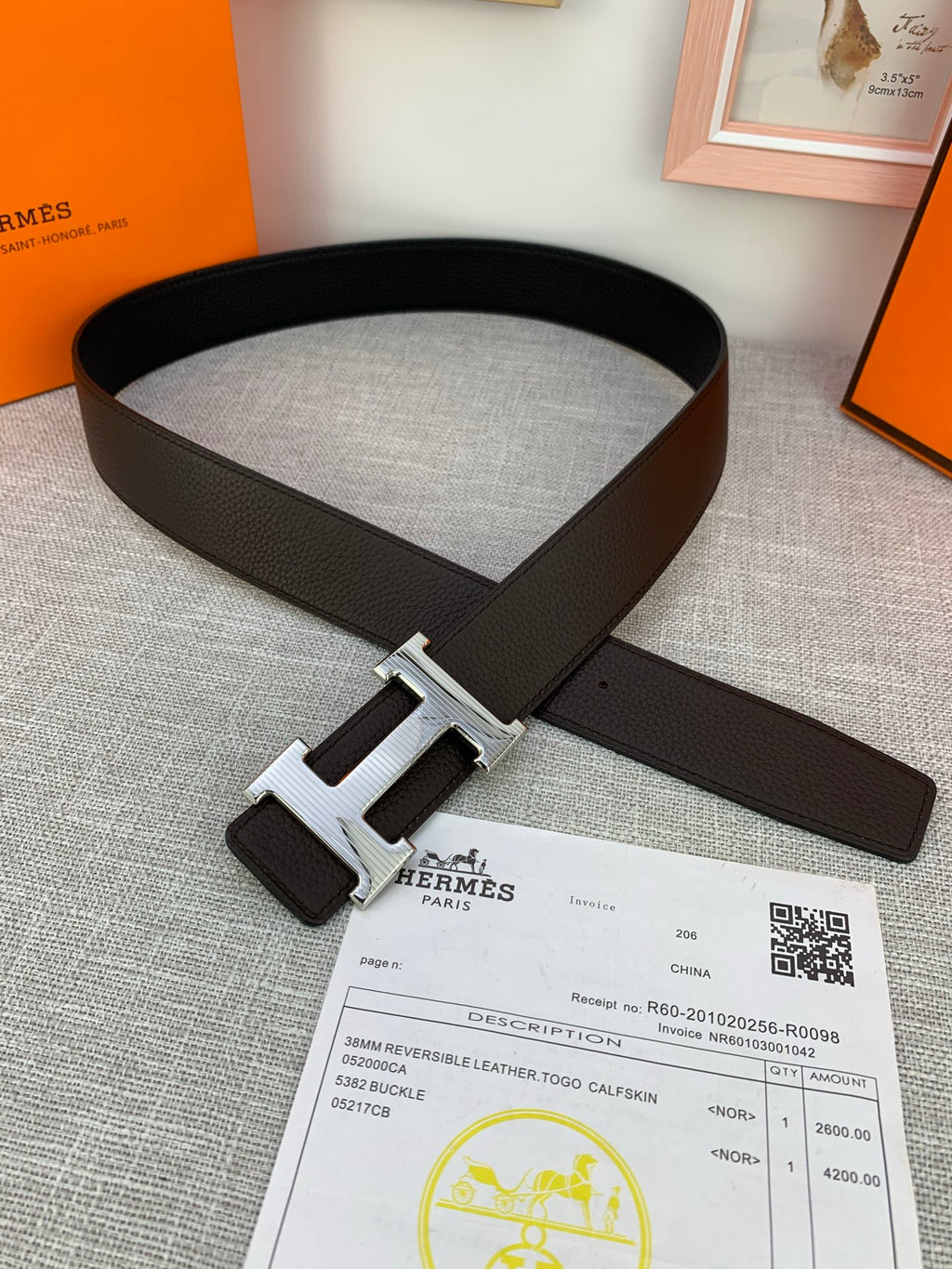 Hermes belt dark leather with silver-toned buckle on top of paperwork