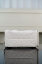 Chanel bag in white quilted leather clutch style with gold chain strap and flap clasp.