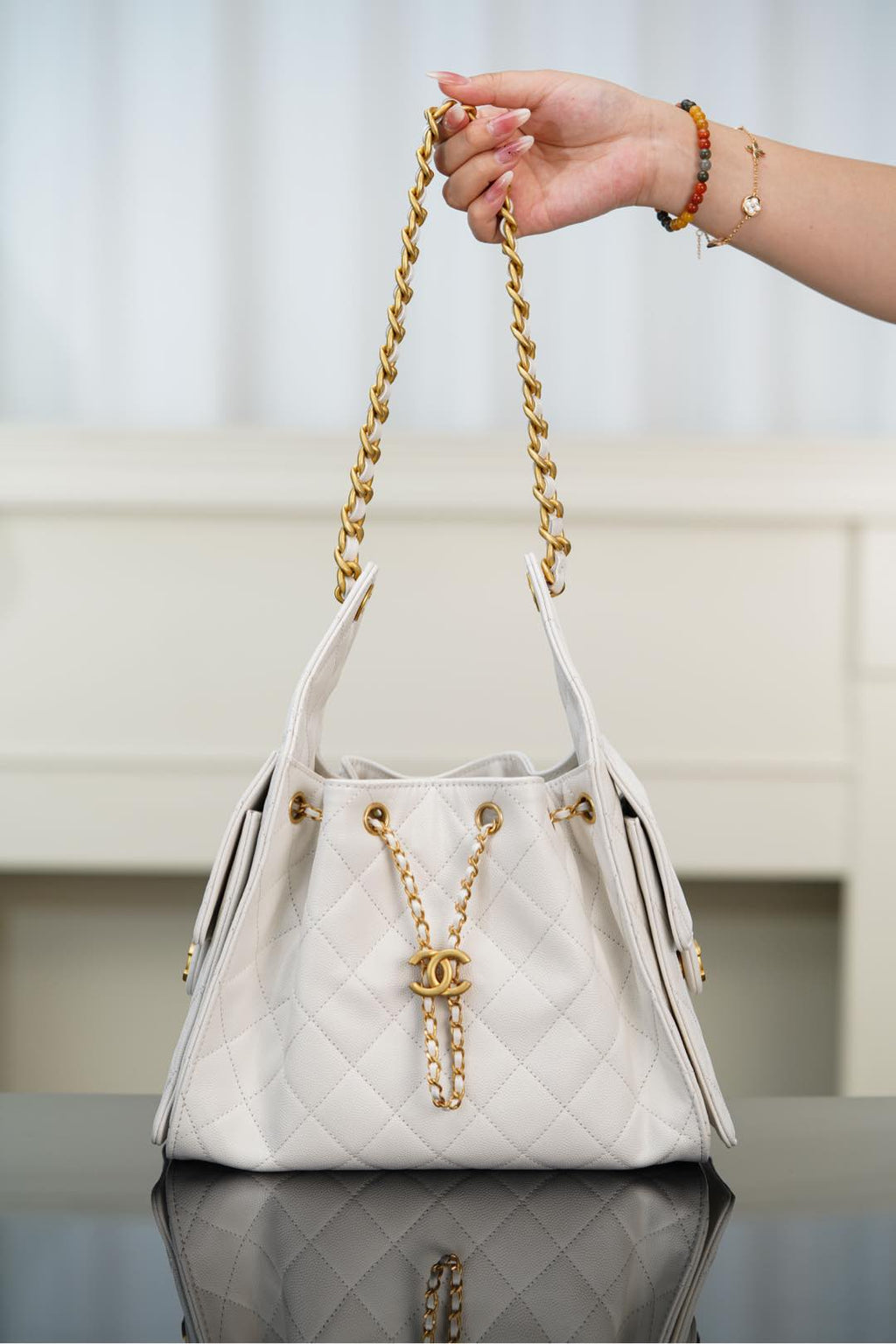 Chanel bag in white quilted leather with gold chain handle and CC pendant detail.
