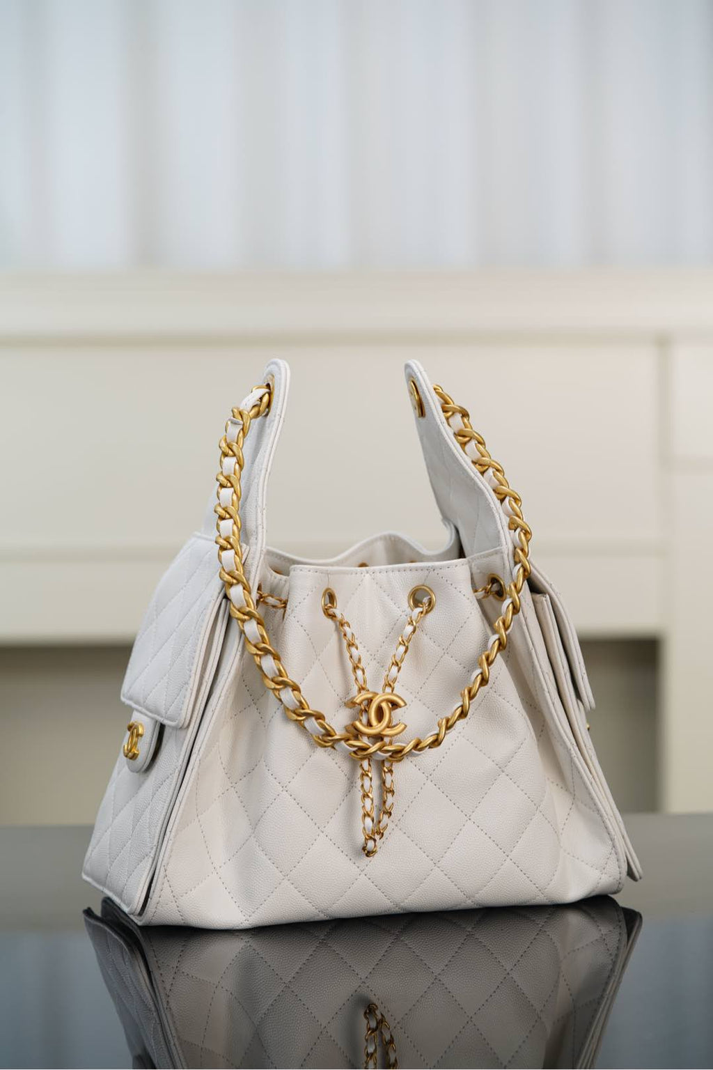 Chanel bag in white quilted leather with gold chain handle and front CC clasp.