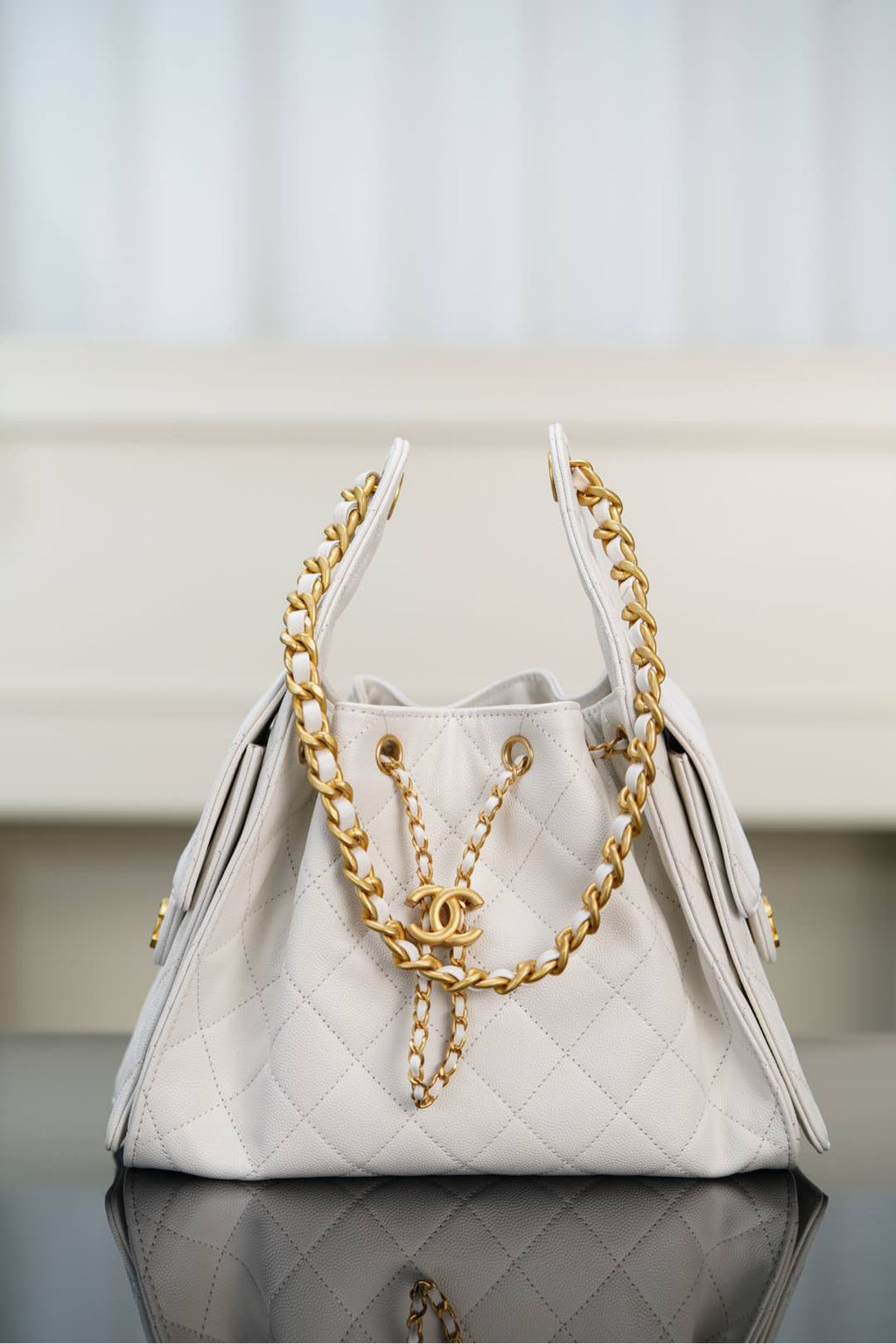 Chanel bag in white quilted leather with gold chain handles and CC clasp.
