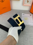 Hermes belt in hand with navy leather strap and silver H buckle, with certificate card