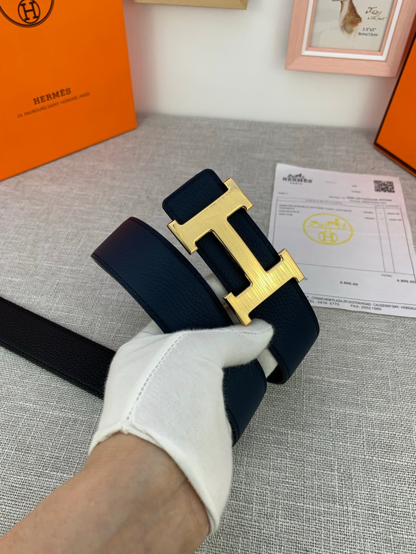 Hermes belt in hand with navy leather strap and silver H buckle, with certificate card