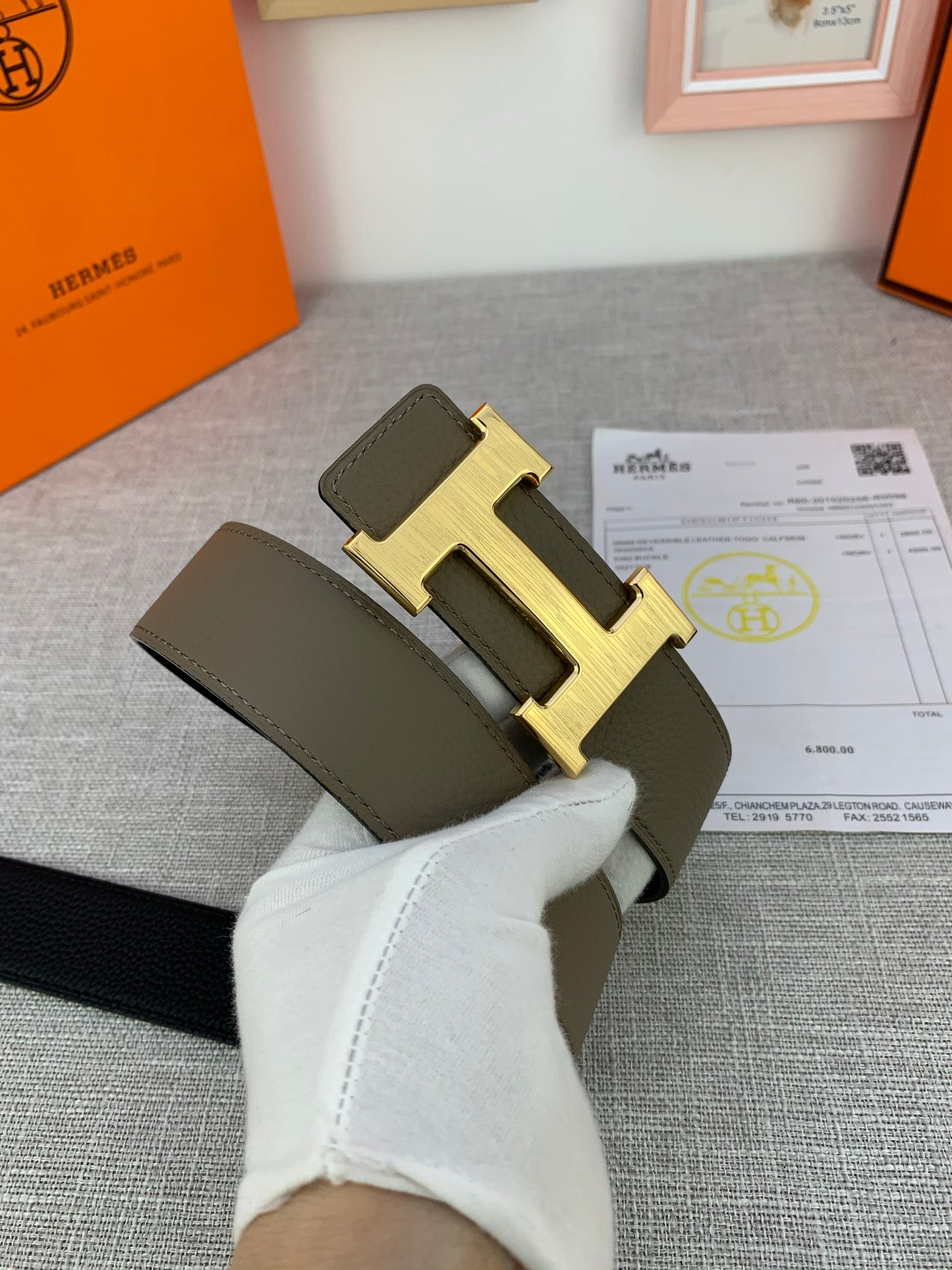 Reversible leather belt close-up of olive strap with gold-tone H buckle