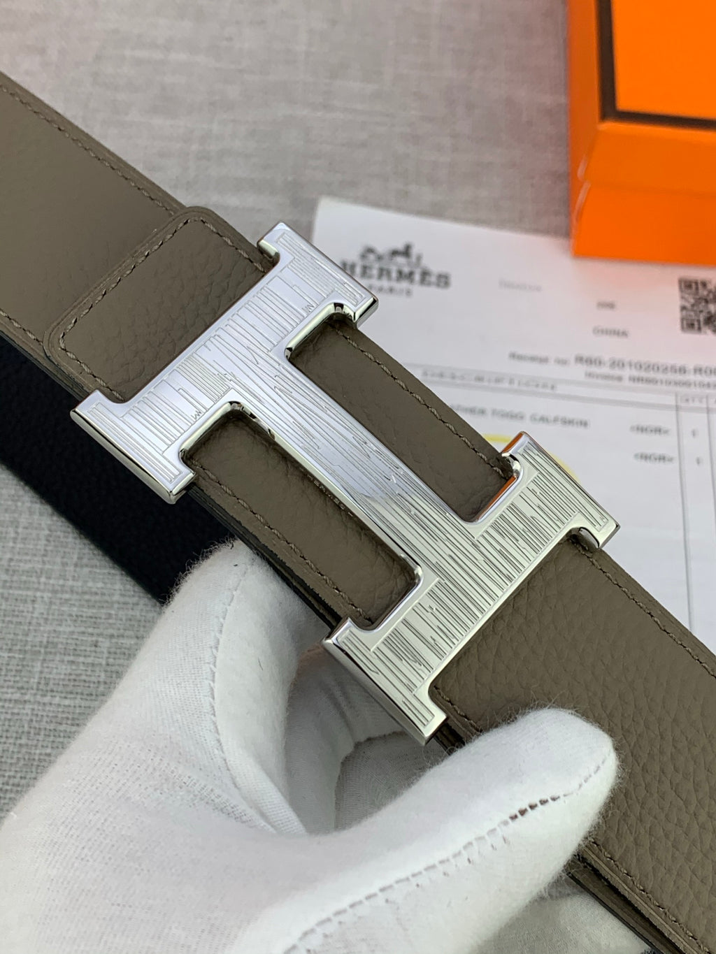 Reversible leather belt close-up of olive strap and silver-tone H buckle