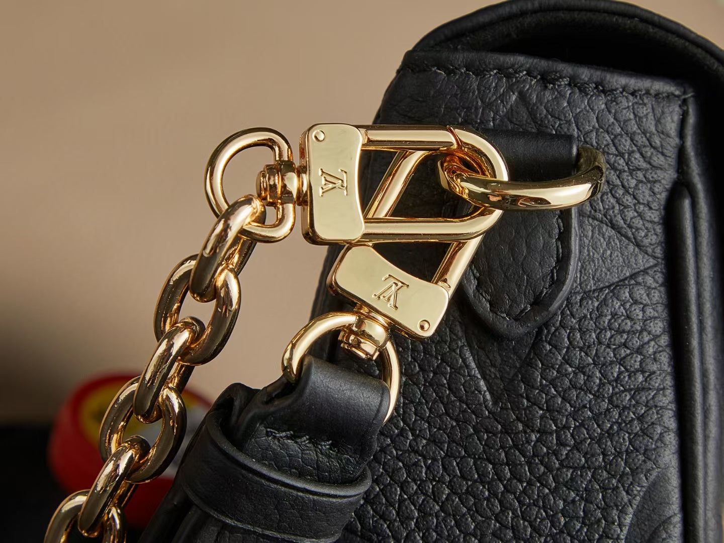 Louis Vuitton gold-tone chain clasp on black textured leather bag