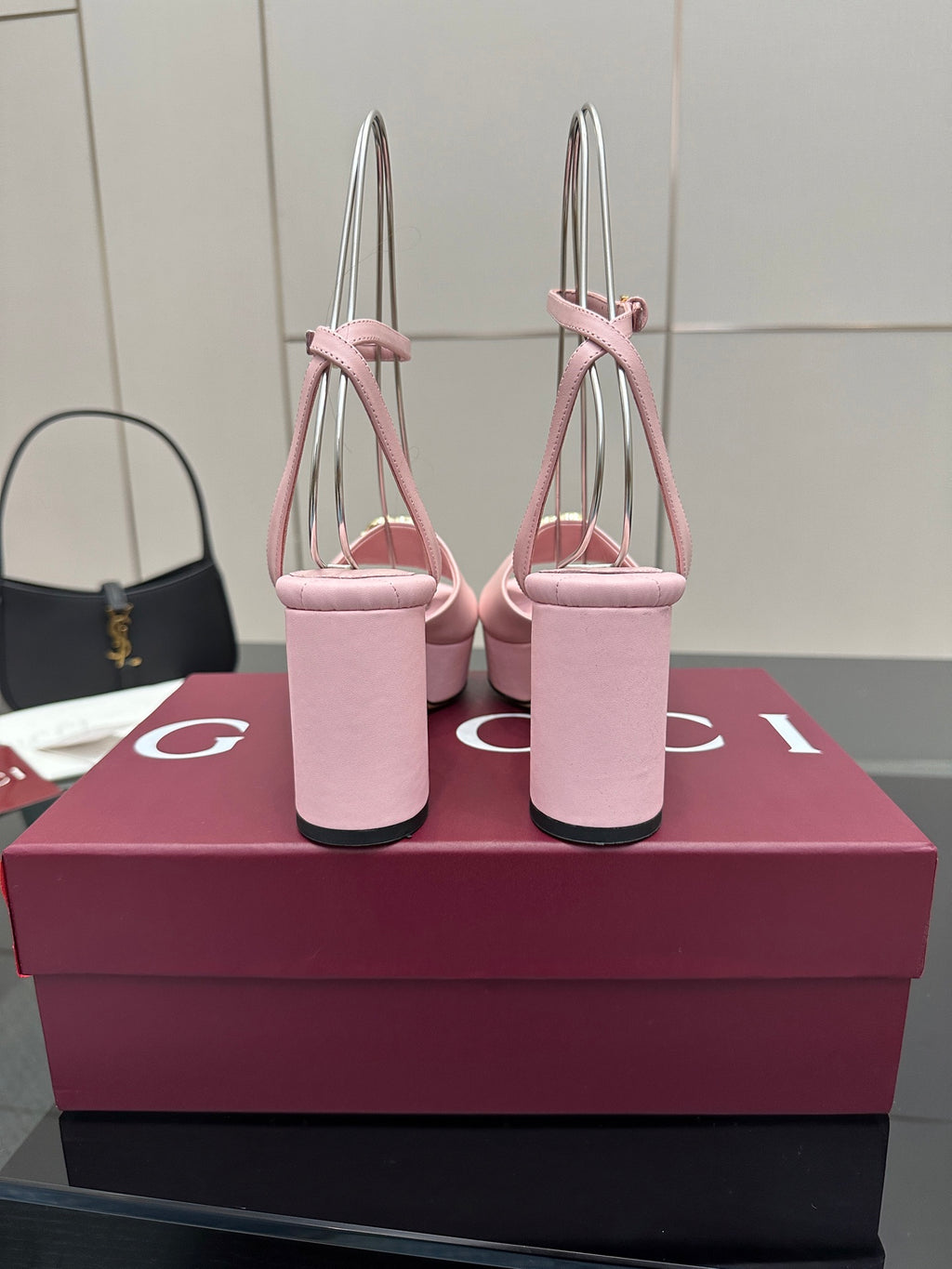 Pink open-toe platform sandals with tall stacked heel and gold logo buckle on strap.