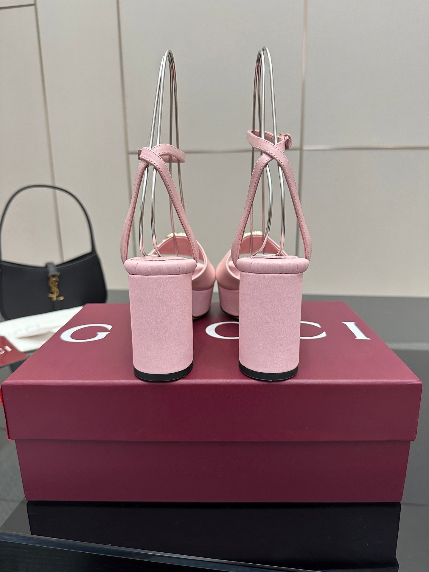 Pink open-toe platform sandals with tall stacked heel and gold logo buckle on strap.