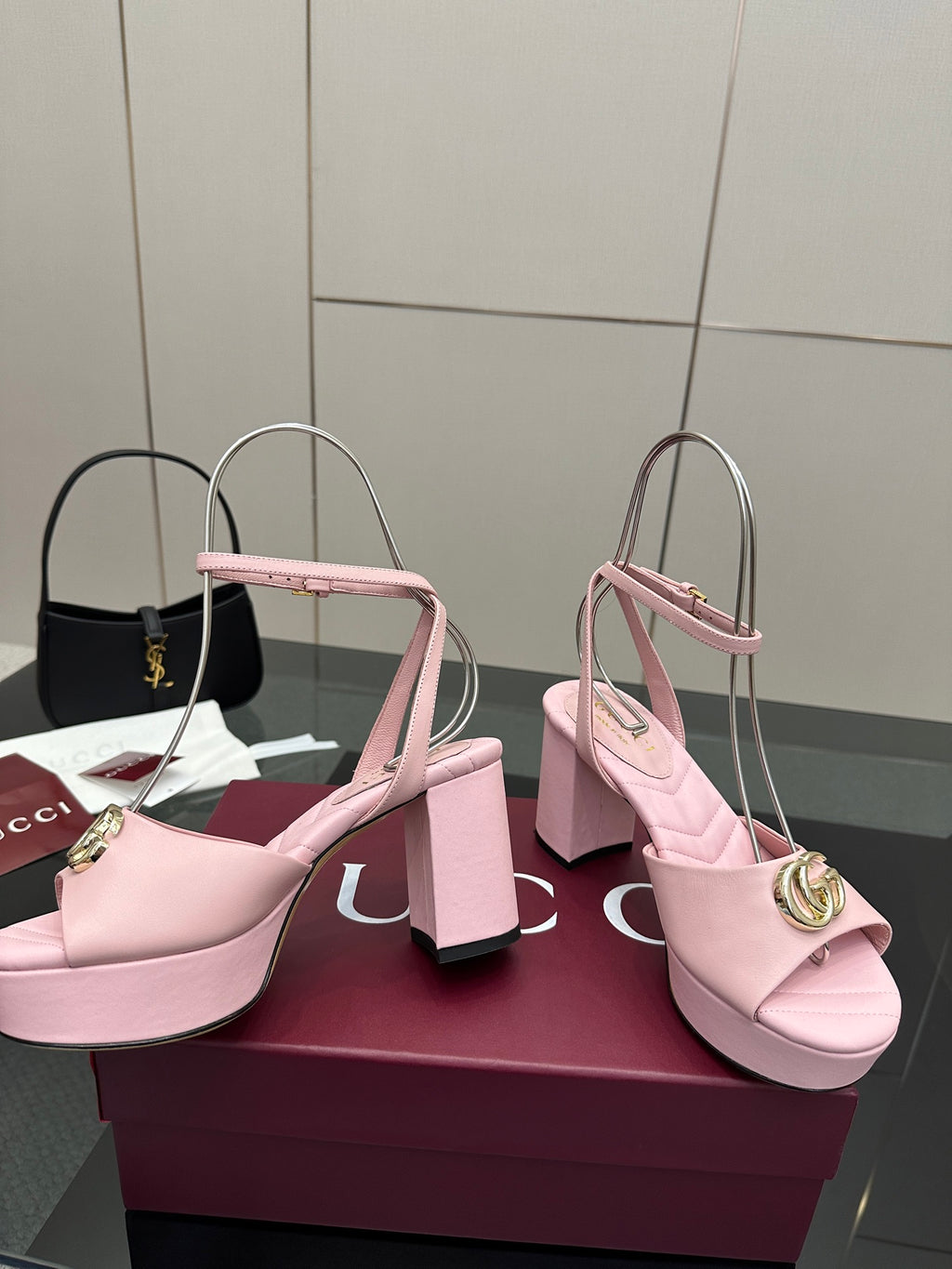 Pink heeled slingback sandals with open toe and gold circular logo buckle detail.