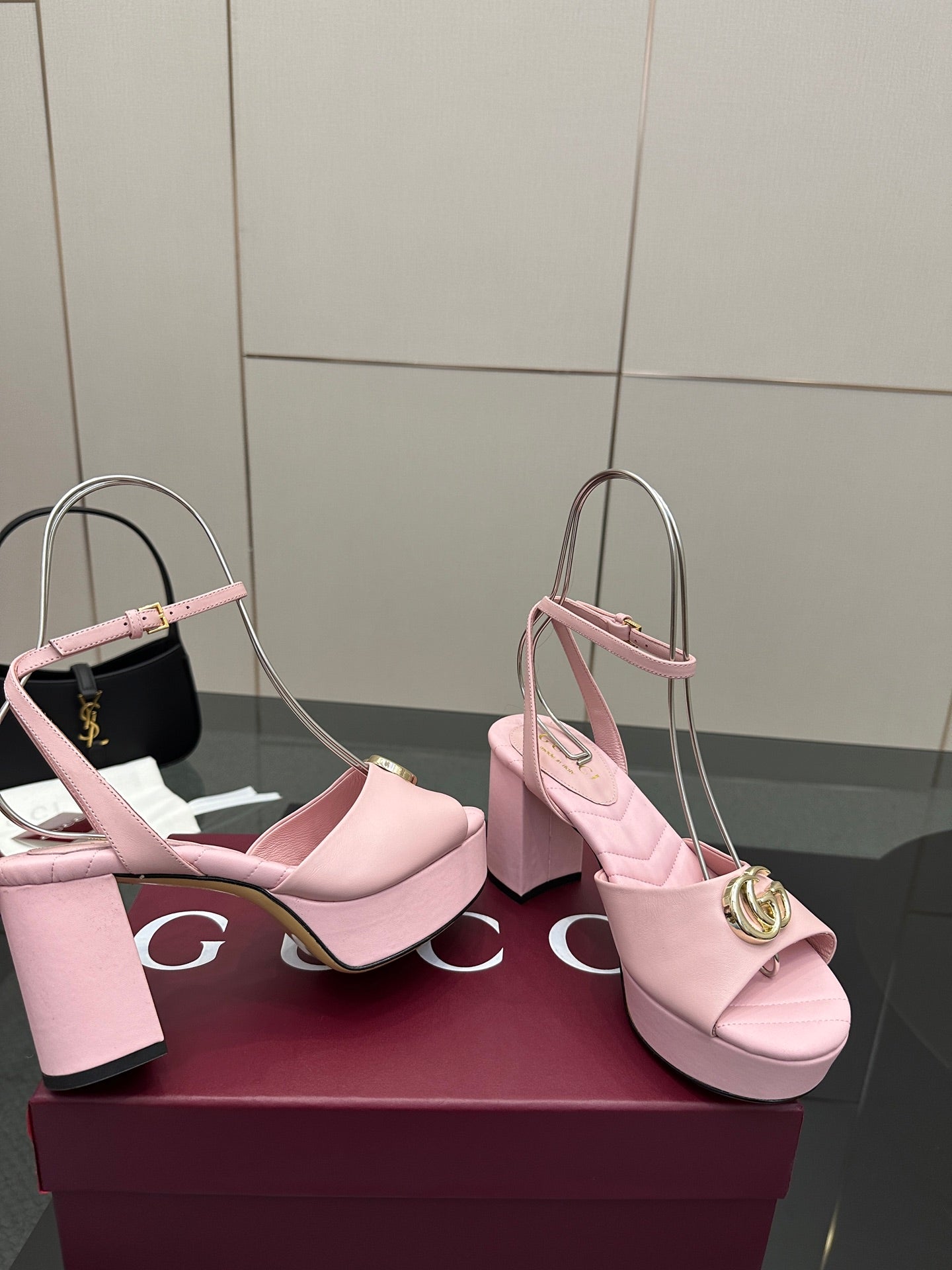 Pink heeled sandals with thick heel and slingback strap, gold logo buckle at toe strap.