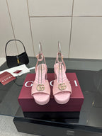 Pink heeled sandals with gold logo buckle and slingback ankle straps, open toe.