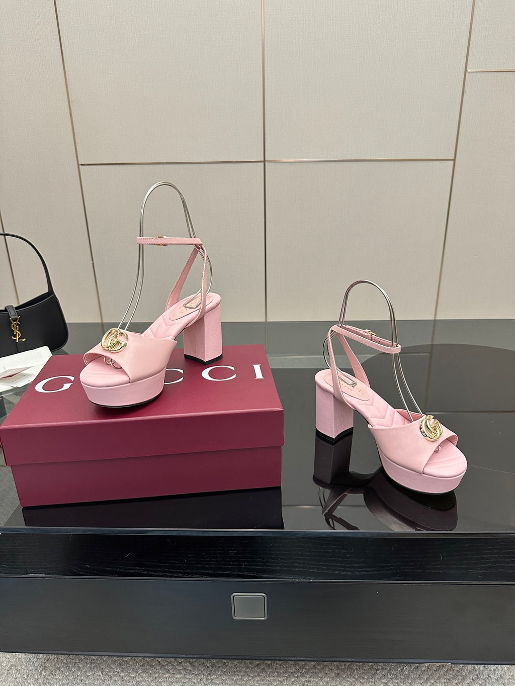 Pink heeled sandals with open toe, slingback straps, and gold logo buckle at front.