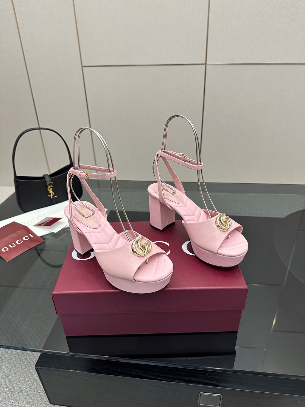 Pair of pink heeled sandals with gold logo buckle, slingback straps, open toe.