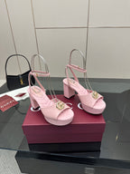 Pair of pink heeled sandals with gold logo buckle, slingback straps, open toe.