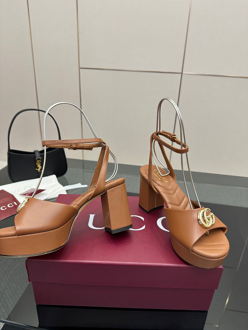 Tan heeled sandals with open toe, ankle strap, and gold GG buckle on block heel