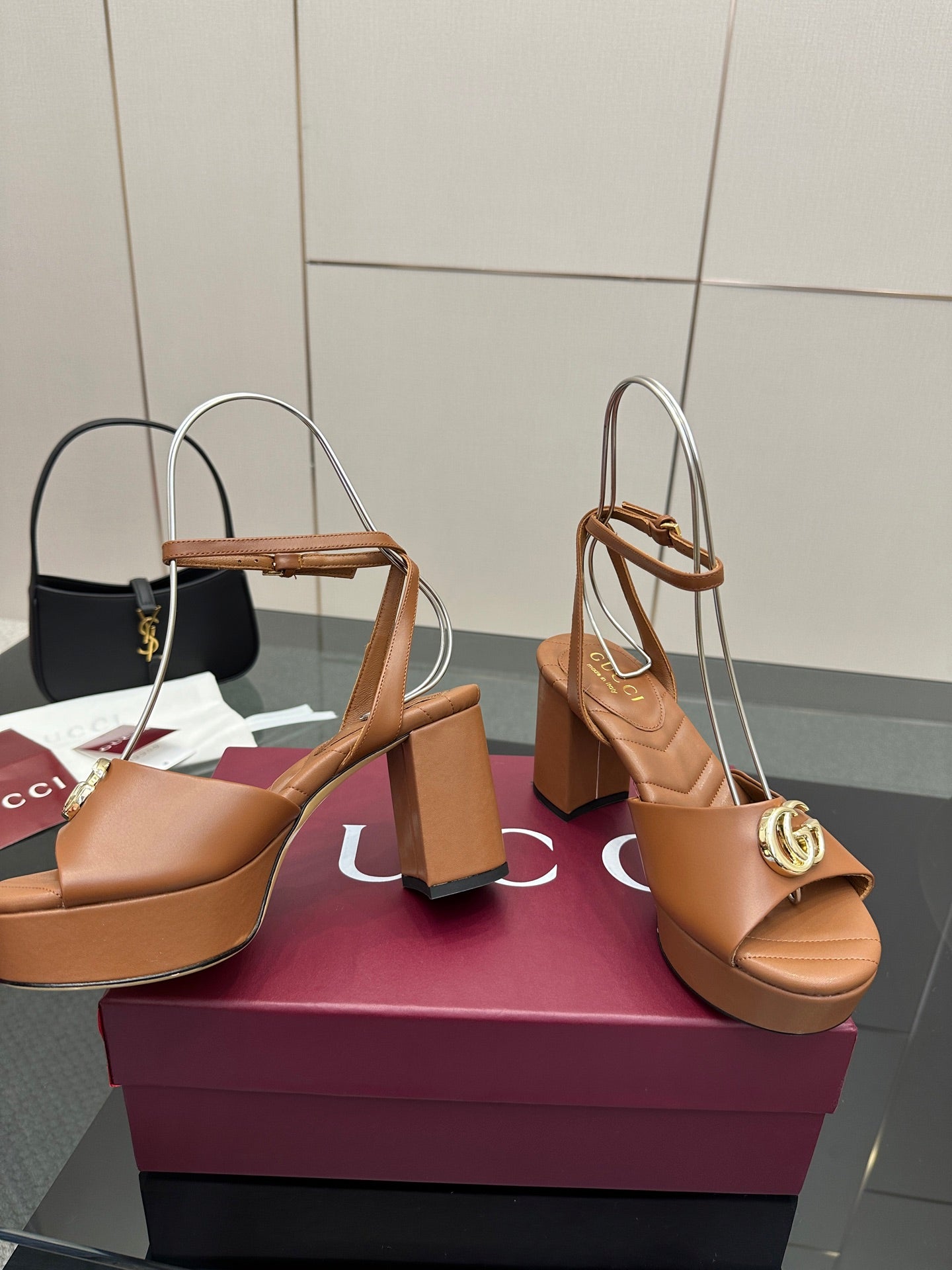 Tan heeled sandals with open toe, ankle strap, and gold GG buckle on block heel