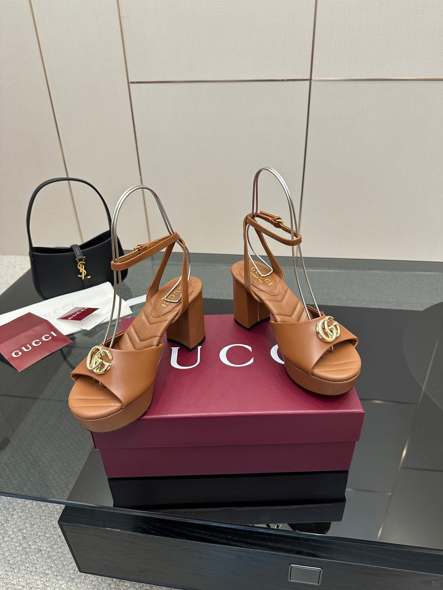 Tan platform heeled sandals with open toe and gold GG buckle, front angled view
