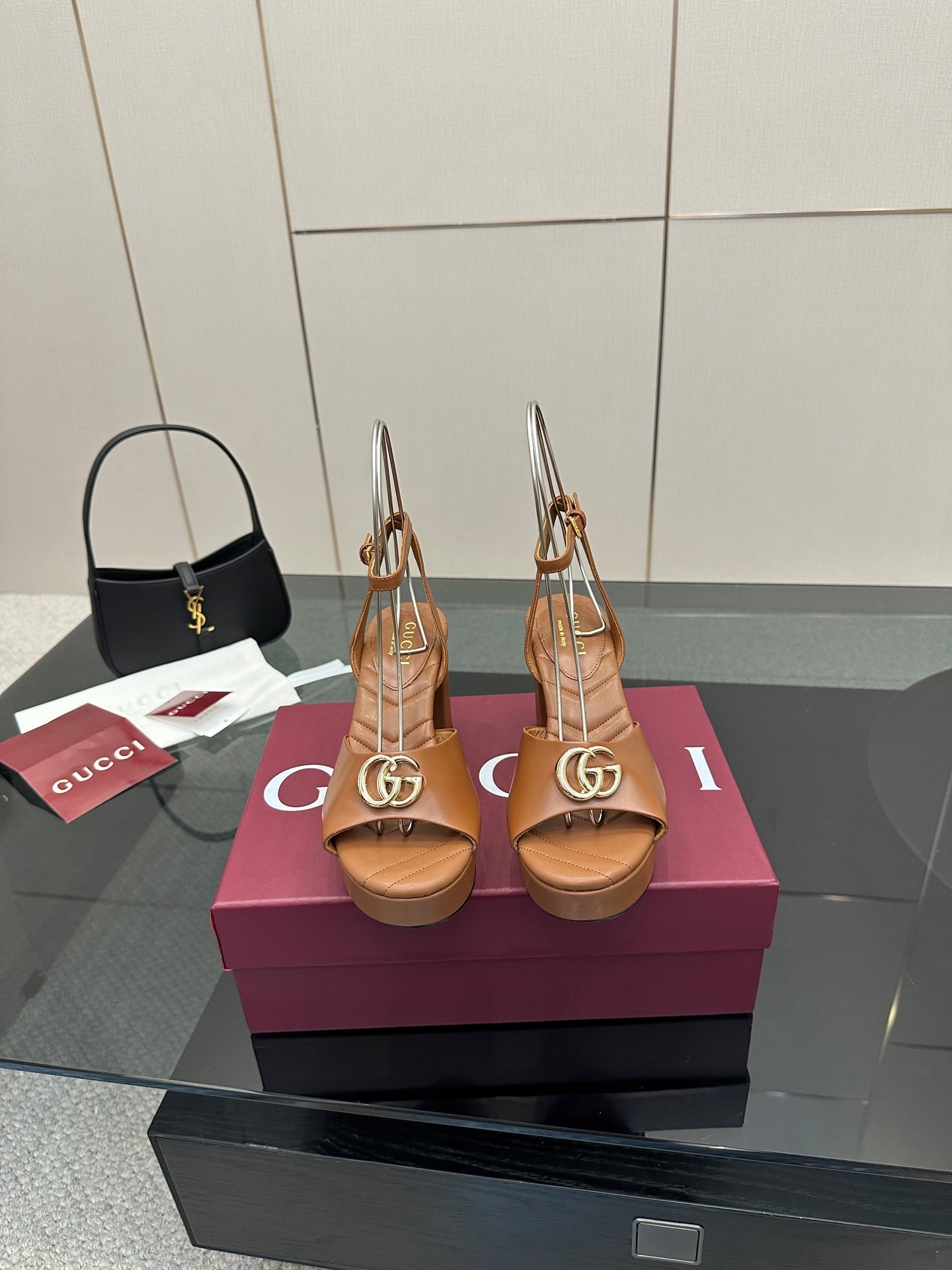 Tan heeled sandals with open toe, ankle strap, and gold GG buckle detail