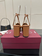 Back view of tan heeled sandals with open toe and gold GG ankle strap buckles