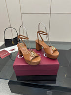 Tan open-toe heeled sandals with ankle strap and gold GG buckle, side view