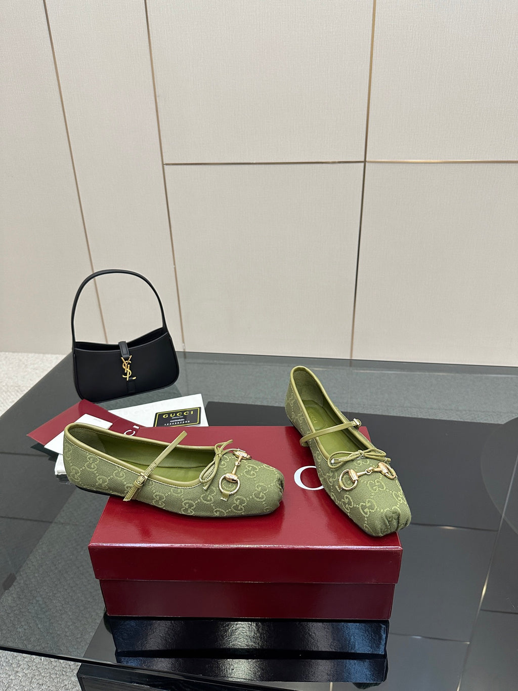 Pair of green patterned Gucci loafers on a red box, side view with horsebit detail