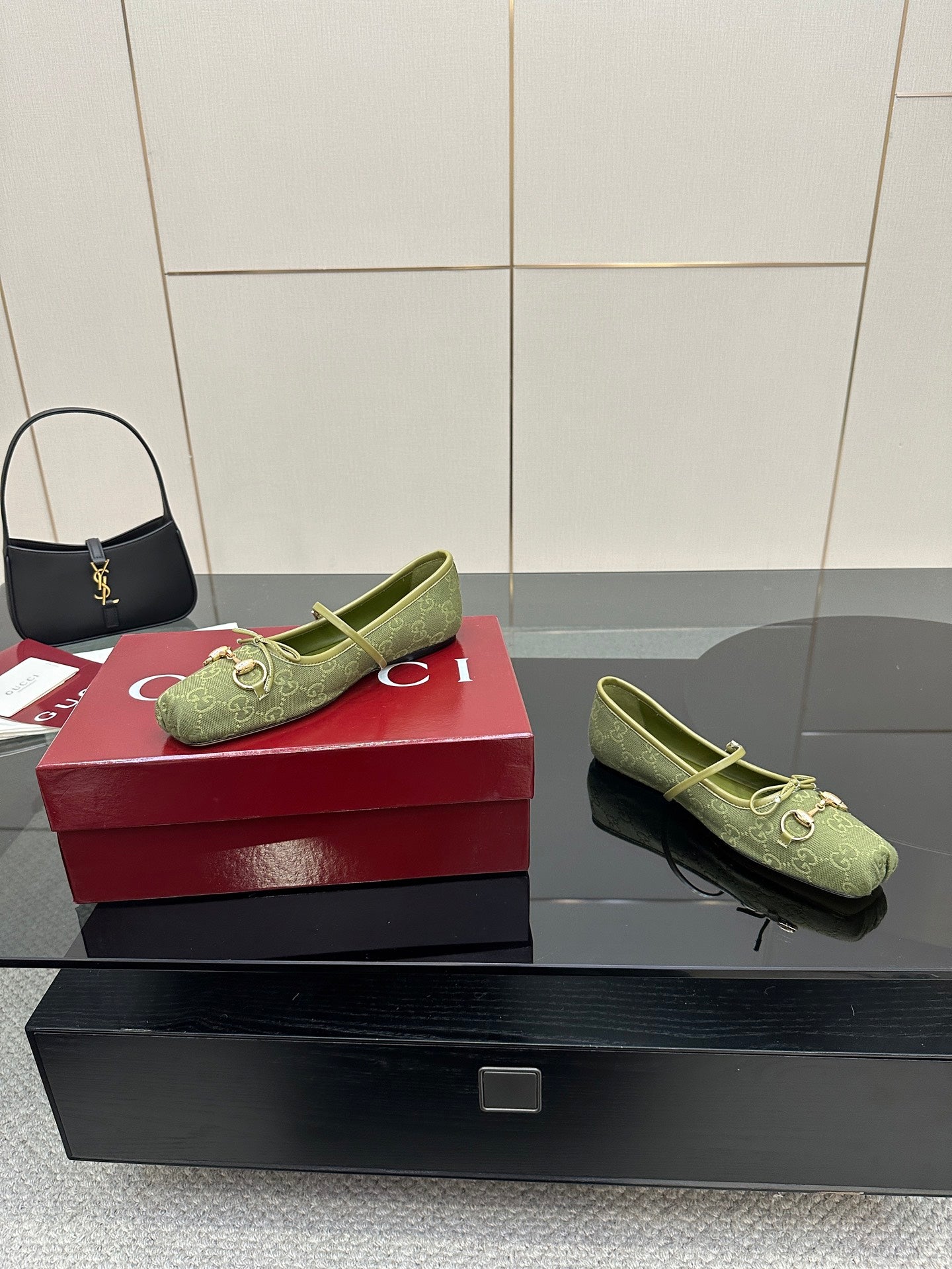 Green patterned Gucci loafers on a red box, angled view with gold-toned horsebit