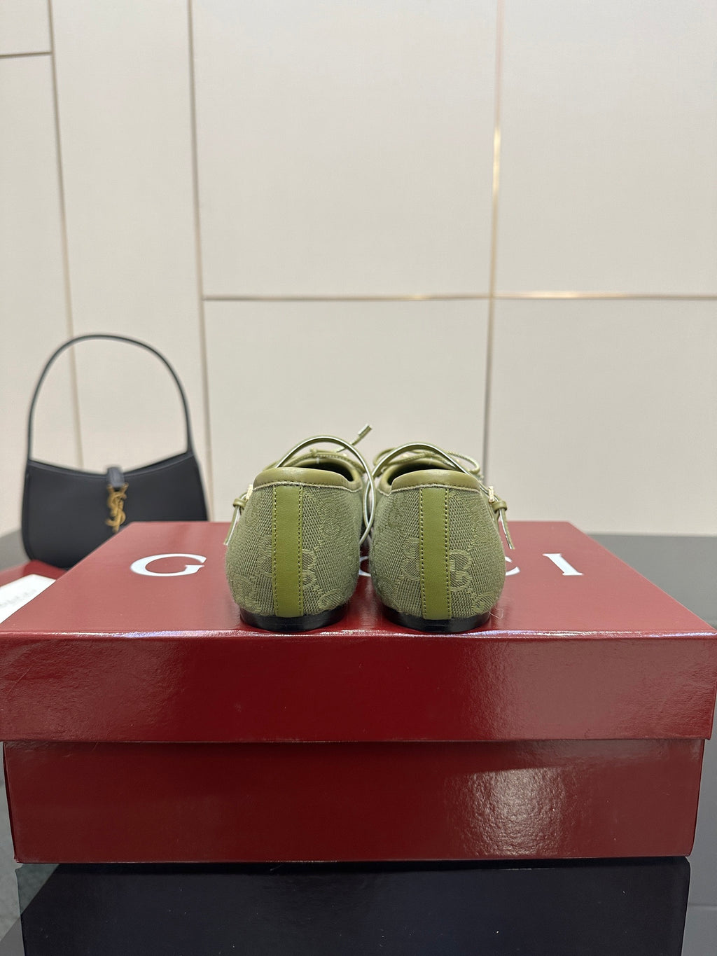 Back view of green patterned Gucci loafers on a red box, heels and toe profile