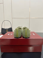 Back view of green patterned Gucci loafers on a red box, heels and toe profile