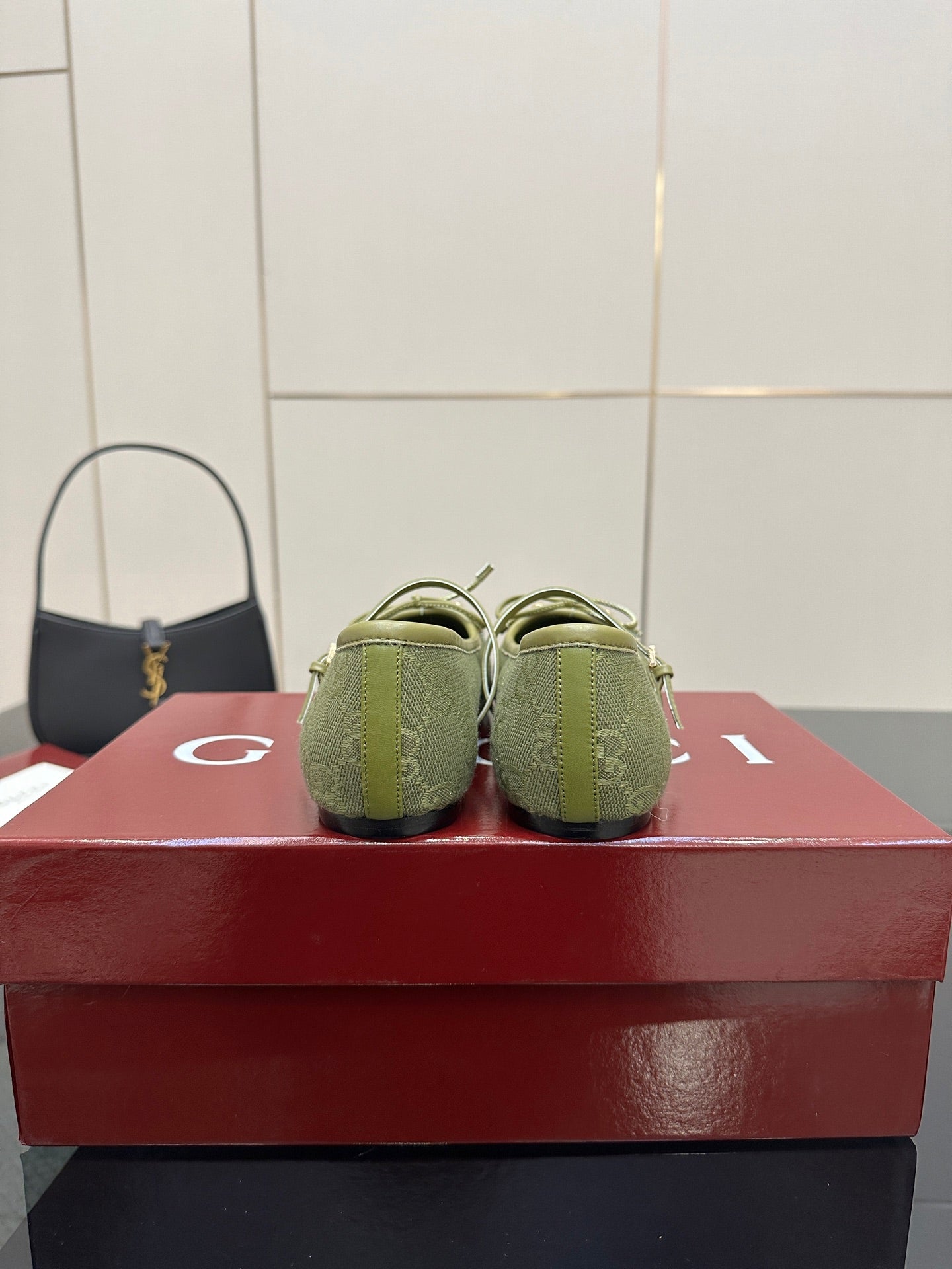 Back view of green patterned Gucci loafers on a red box, heels and toe profile