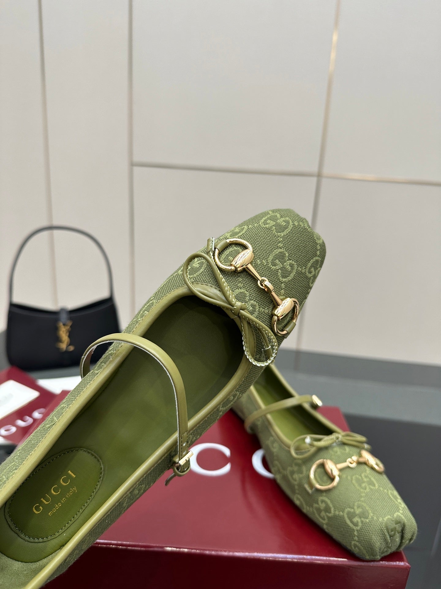 Close-up of green patterned Gucci loafer, showing open top and gold-toned horsebit