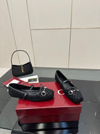 Pair of Gucci black loafers on a red box, with metal bit hardware and laces