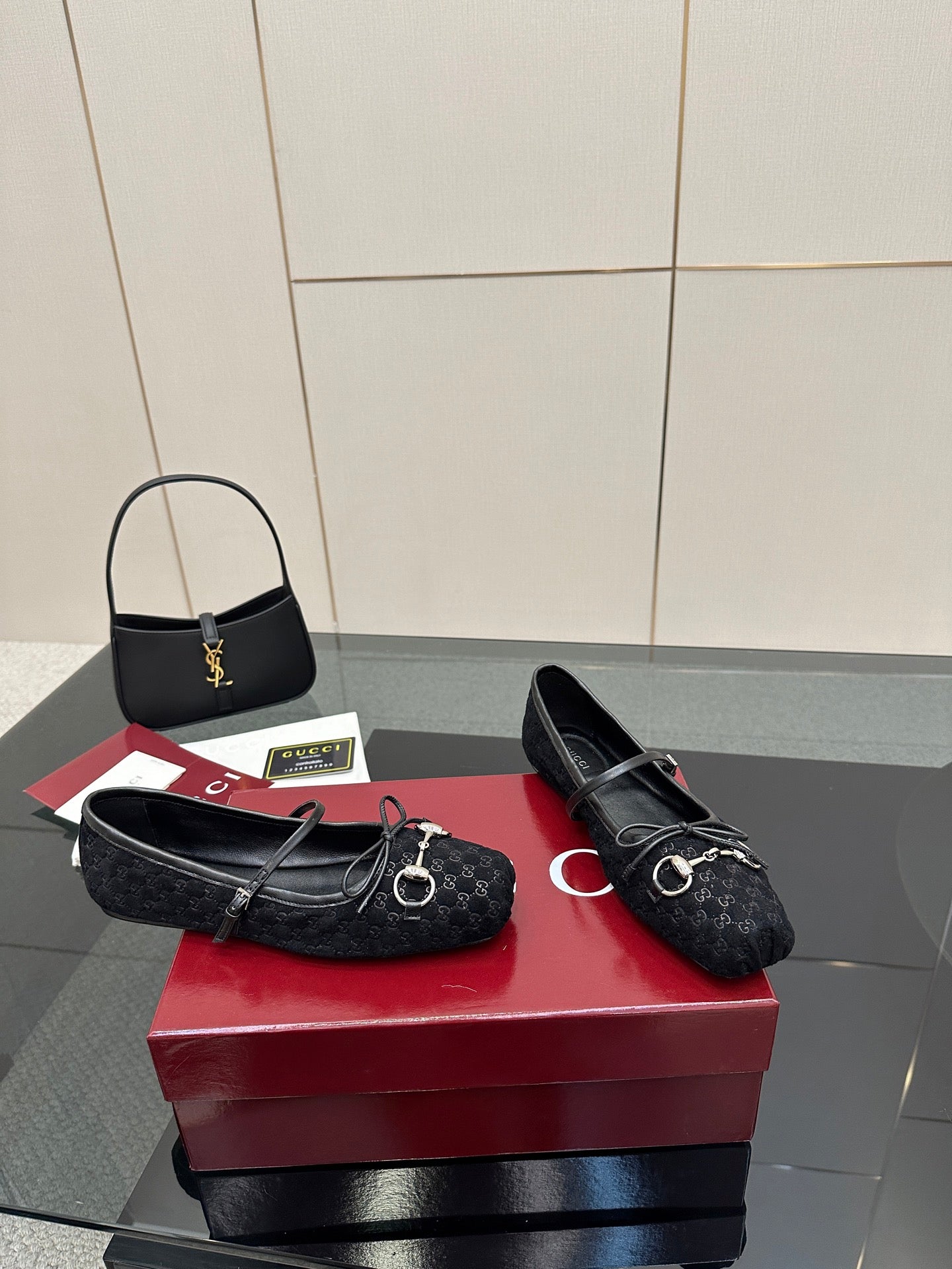 Pair of Gucci black loafers on a red box, with metal bit hardware and laces