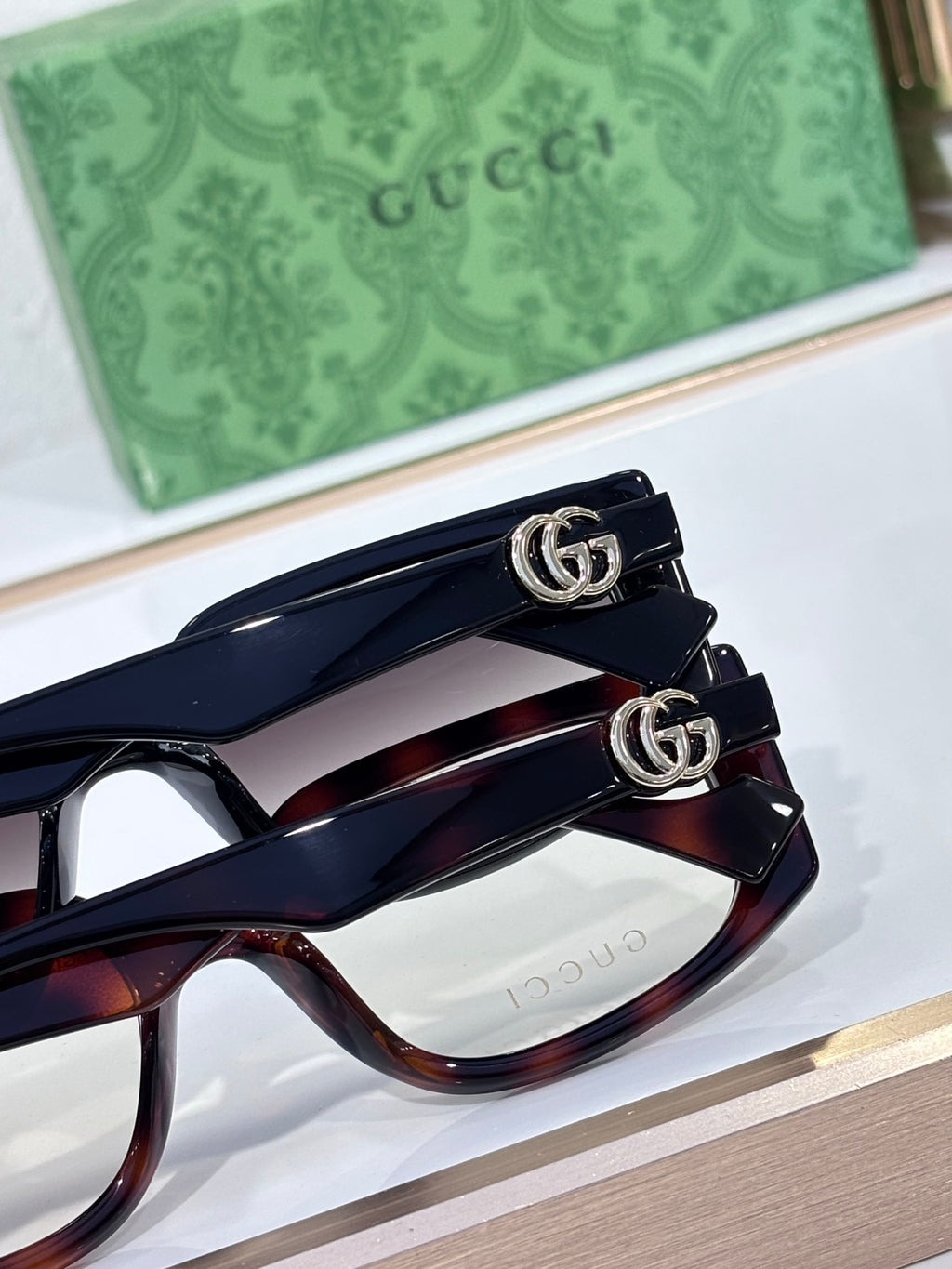 Gucci glasses close-up, tortoiseshell frames with GG metal logo detail