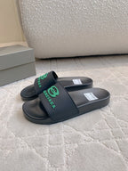 Black Balenciaga slide sandals with green logo strap, side view