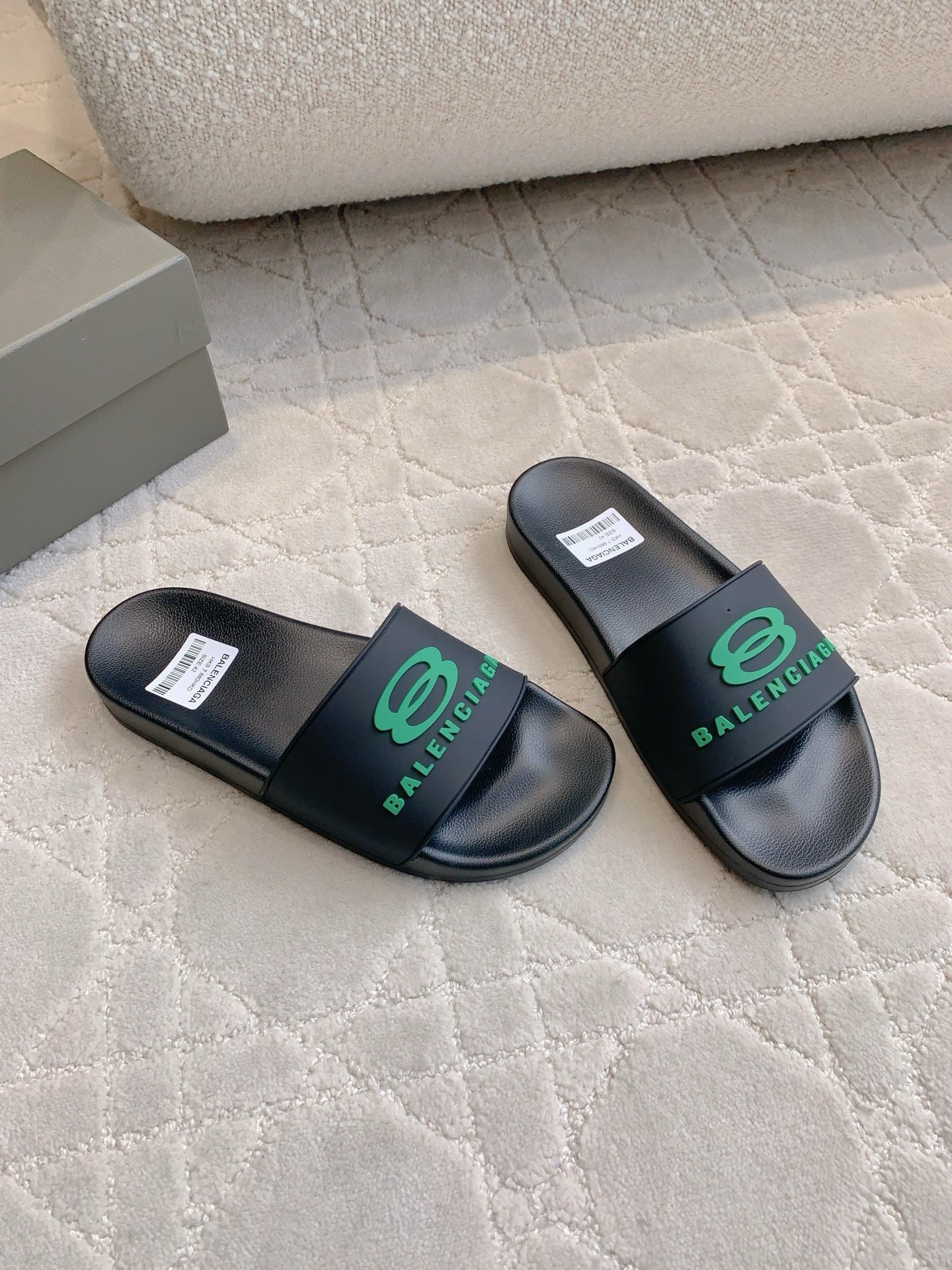 Black Balenciaga slide sandals with green logo strap, angled pair