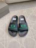 Black Balenciaga slide sandals with green logo strap, pair front