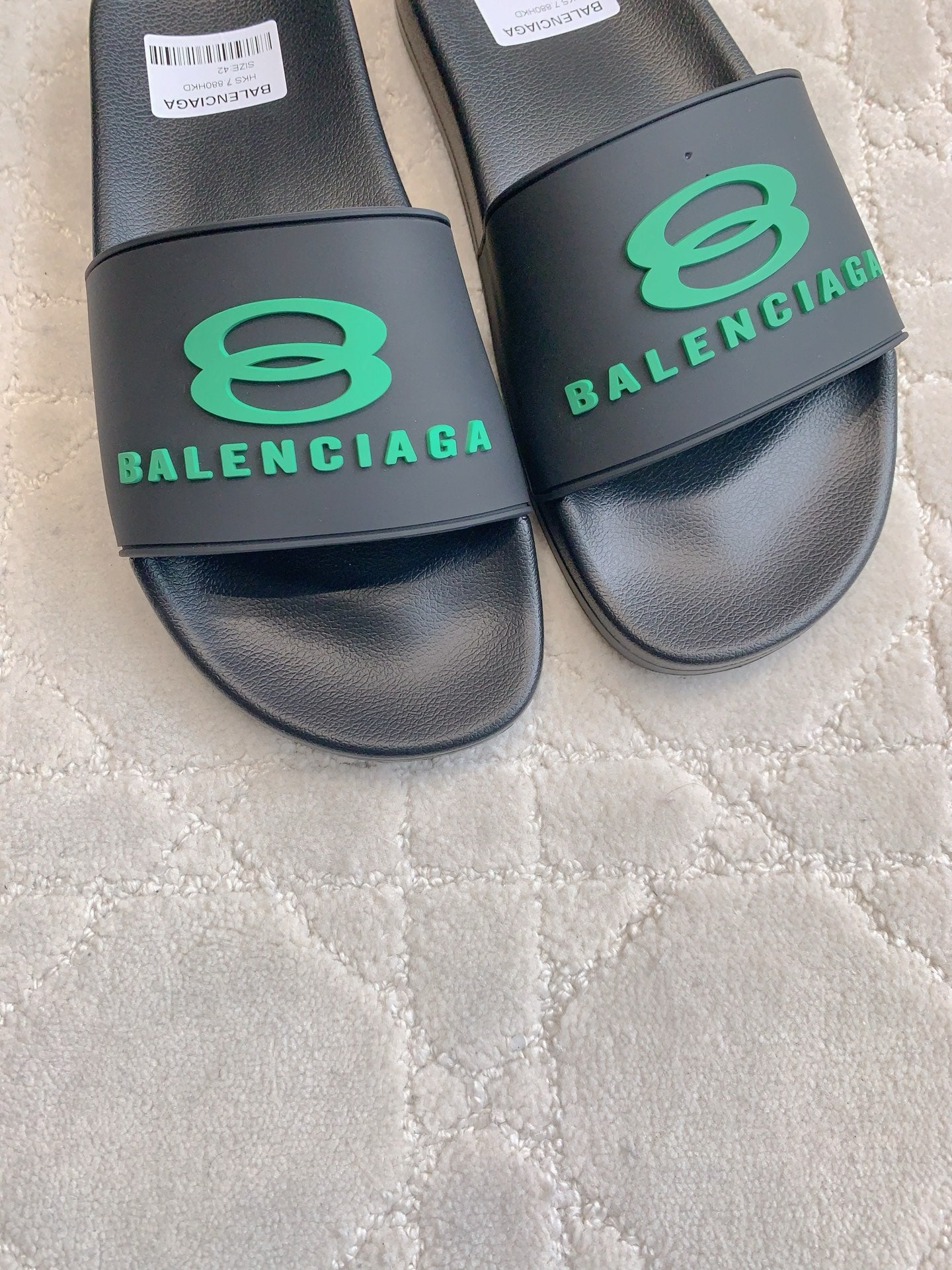 Black Balenciaga slide sandals with green logo strap, close-up