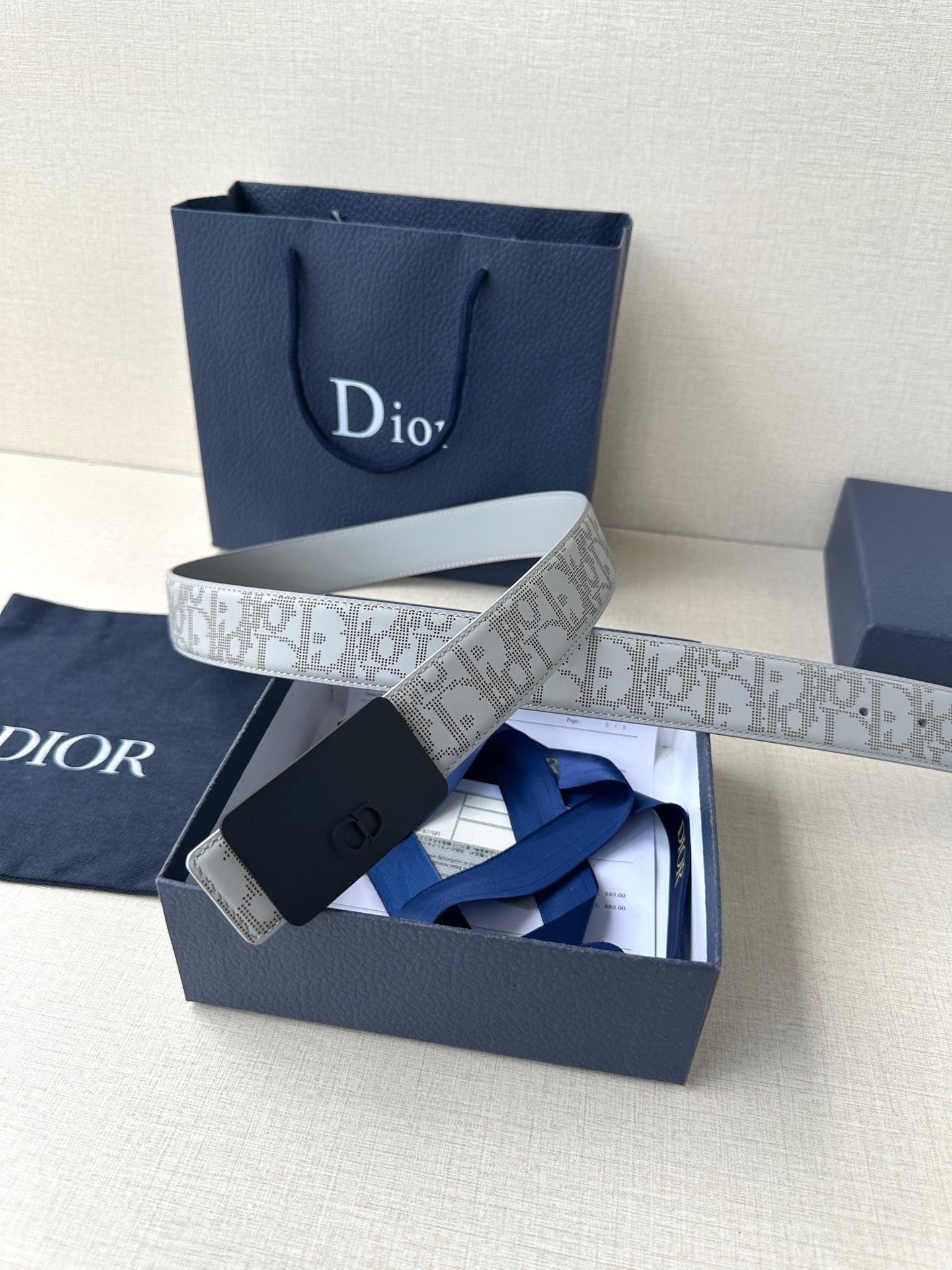 Dior belt with light gray patterned strap and navy buckle, shown in box