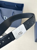 Dior belt close-up with dark navy logo-embossed strap and rectangular silver-toned buckle