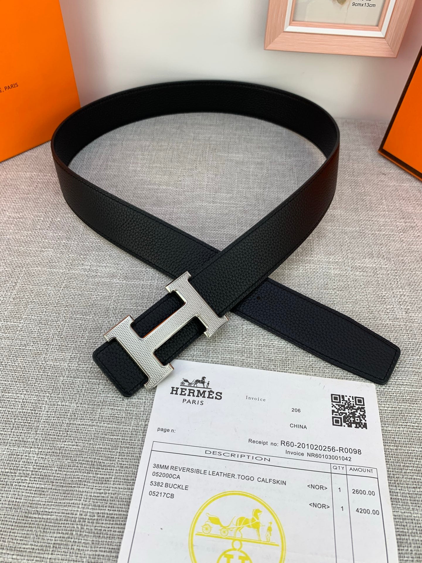 Black Hermes belt laid flat with silver H buckle and keeper tab