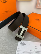 Dark leather belt with silver-tone H buckle shown in an open box