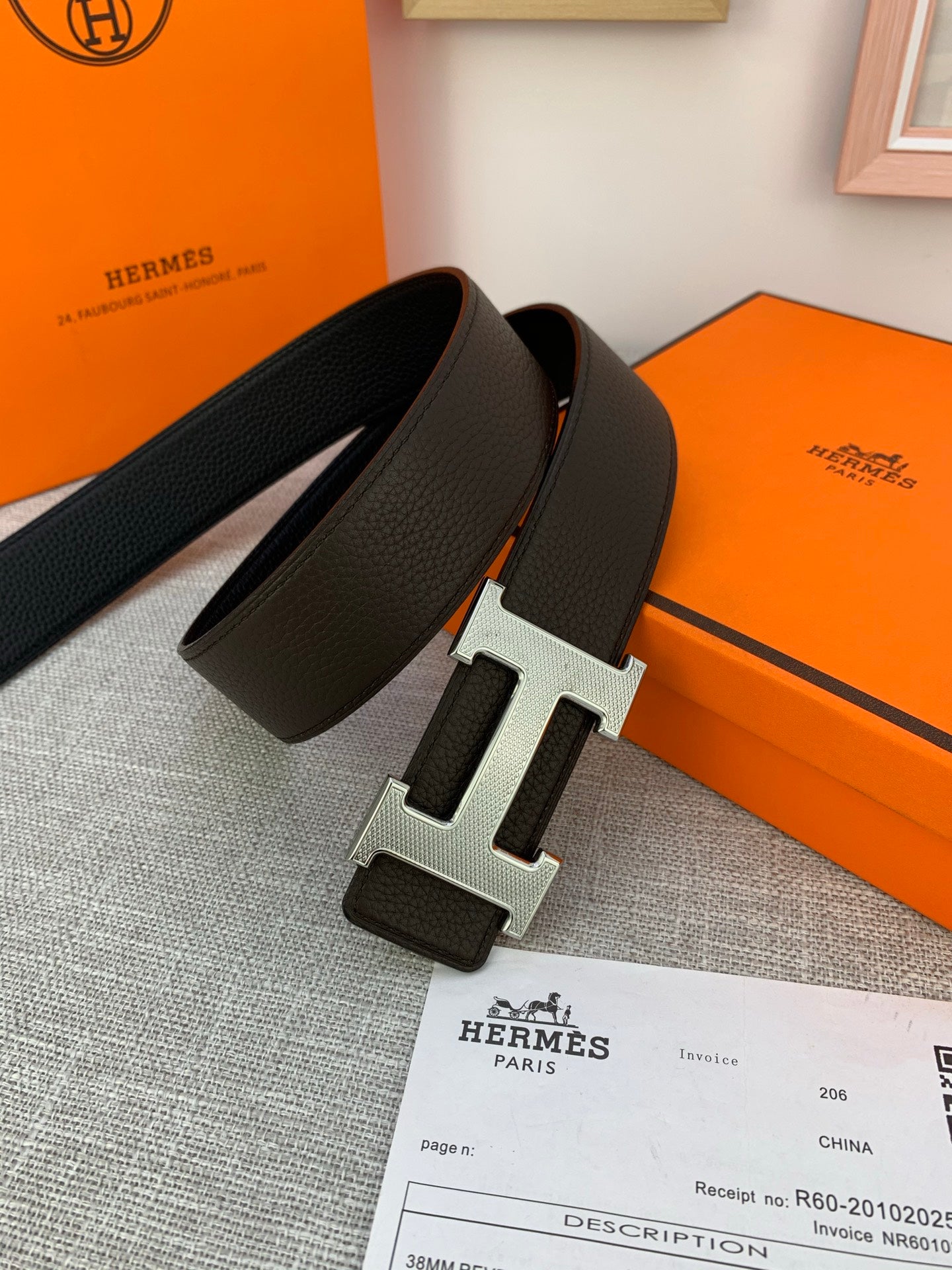 Dark leather belt with silver-tone H buckle shown in an open box